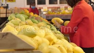 女人在超市购物，买食物，在市场上选择水果，在超市。 购买。